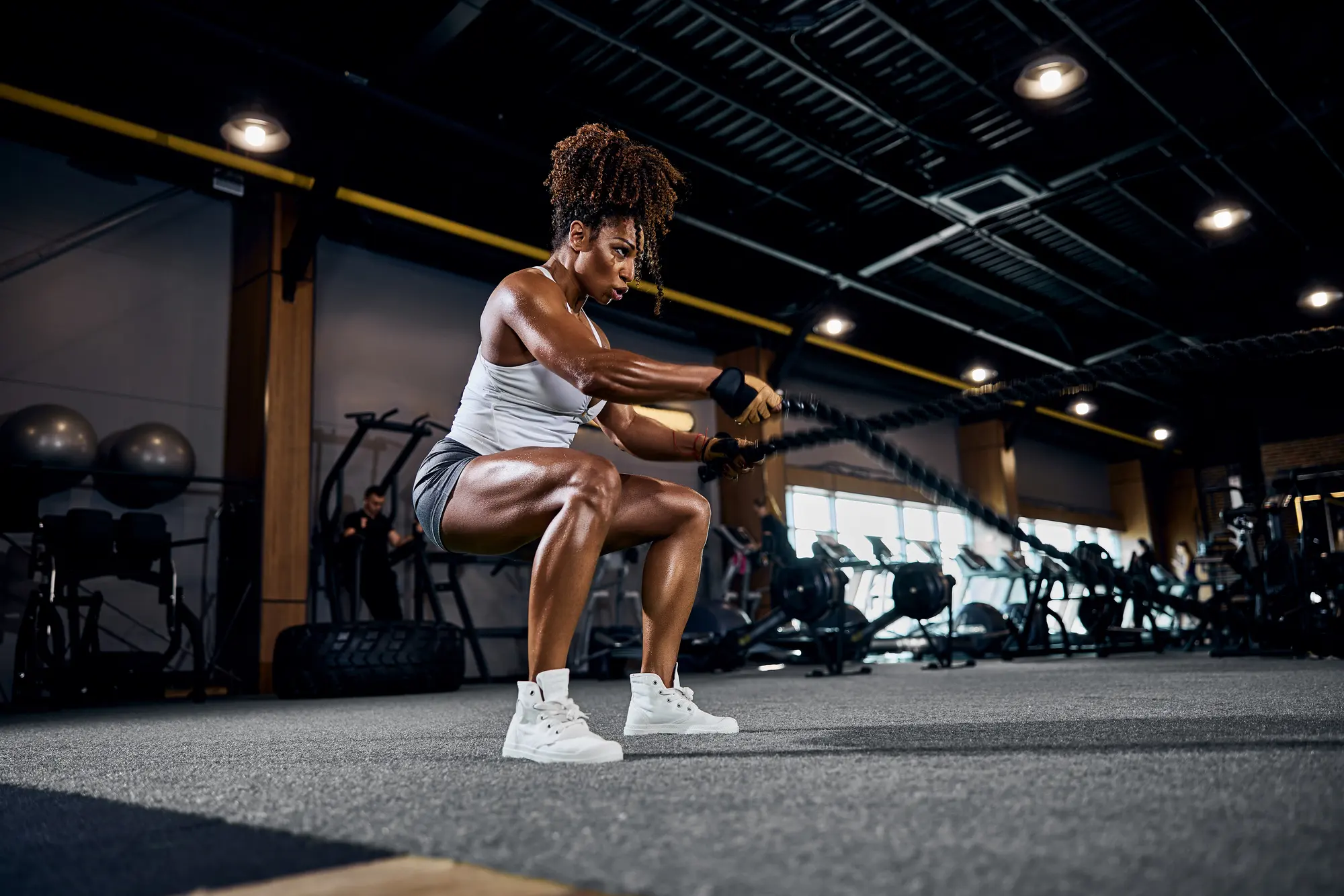 An athlete working battle ropes in a low squat